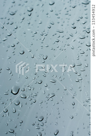 Rain drops on a window glass surface against a dark background of stormy sky. Rain drops on a window glass surface against a dark background of stormy sky. 133454912