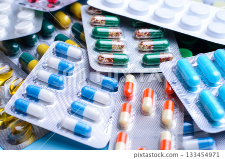 Pile of pills and capsules prescribed for different illnesses packed in foil packaging 133454971