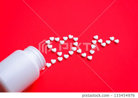 Concept of treatment for heart diseases. Pills in the shape of small hearts making cardiogram sign on red background 133454976