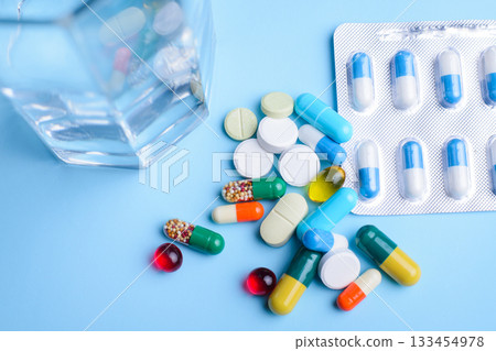Top view of medicine on the blue table before taking them by ill or sick person. Big daily dose of pills and capsules for treatment difficult cases of diseases 133454978