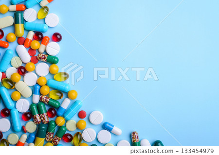 Medicine background of capsules pills of different size, color on light blue table. Concept of treatment, illness. 133454979
