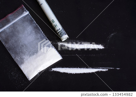 Small plastic bag with white powder drugs with two lines ready for inhaling by drug abuse person Small plastic bag with white powder drugs with two lines ready for inhaling by drug abuse person 133454982