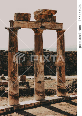 Ancient pillars in a historical site The image features three aged pillars, remnants of an ancient structure set against a rustic backdrop, hinting at a rich history. Ancient pillars in a historical site The image features three aged pillars, remnants of an ancient structure set against a rustic backdrop, hinting at a rich history. 133455080