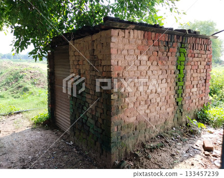 An old brick barn in the India countryside with a corrugated asbestos roof. An old brick barn in the India countryside with a corrugated asbestos roof. 133457239