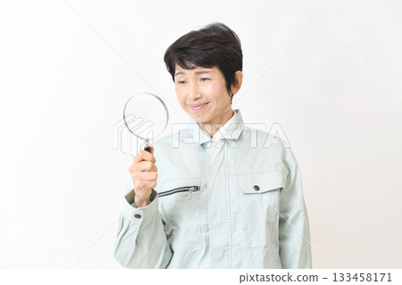 一位身穿工作服的中年亞裔女性手持放大鏡 一位身穿工作服的中年亞裔女性手持放大鏡 133458171