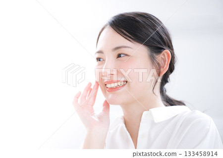 Close-up of a beauty portrait of a young woman in a white shirt with a clean look, smiling and showing skin care and beautiful skin Close-up of a beauty portrait of a young woman in a white shirt with a clean look, smiling and showing skin care and beautiful skin 133458914