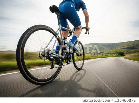 Spirited cyclist on a modern gravel bike speeding down a winding country road 133460872