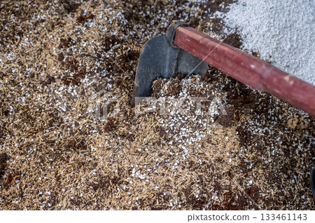 Gardener using a hoe for mix and blend coconut coir, rice husks, cow dung and Perlite for making potting soil. This soil is a soilless, man-made substrate specifically designed for growing plants. Gardener using a hoe for mix and blend coconut coir, rice husks, cow dung and Perlite for making potting soil. This soil is a soilless, man-made substrate specifically designed for growing plants. 133461143