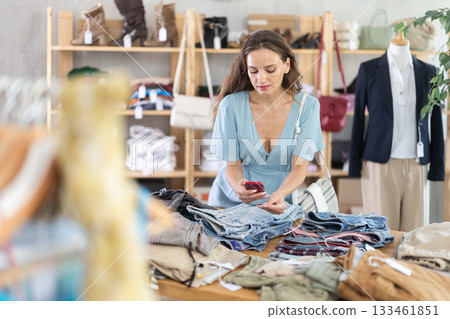 Happy young woman scanning QR-code on pantaloons in clothing store 133461851