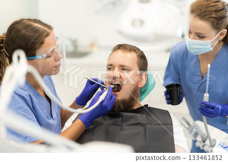 Two women dentists treating a man teeth 133461852