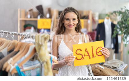 Young woman holding sale banner in clothing store 133461889