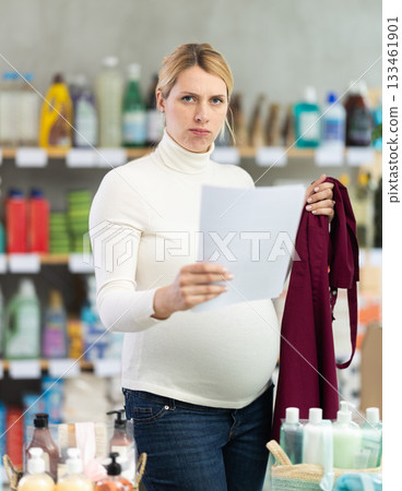 Pregnant saleswoman in store aisle worried over maternity leave terms 133461901