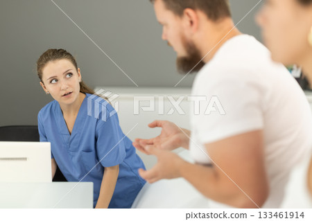 Man stands near the reception and asks questions to the administrator in the dentistry 133461914