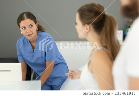 Woman stands near the reception of the dentistry and communicates with the administrator 133461915
