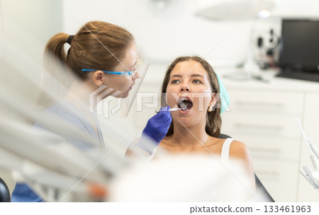 Female doctor checks young woman teeth during visit to dental clinic Female doctor checks young woman teeth during visit to dental clinic 133461963