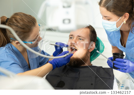 Two women dentists treating a man teeth 133462157
