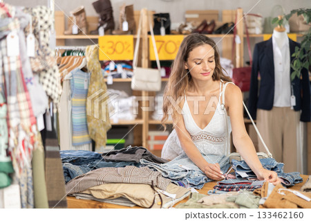 Positive young woman choosing pantaloons in clothing store Positive young woman choosing pantaloons in clothing store 133462160
