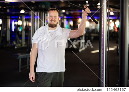 Young man posing by arm exercise machine Young man posing by arm exercise machine 133462167