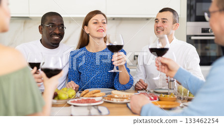 Friends enjoying informal dinner and conversations at kitchen table 133462254