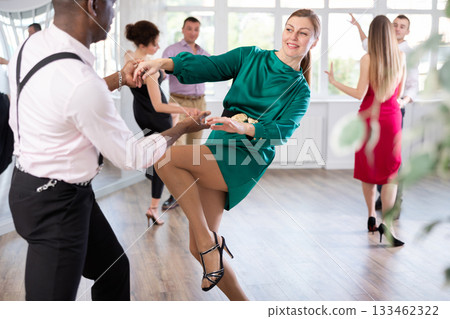 Woman and man dancing foxtrot in pair during group dance party Woman and man dancing foxtrot in pair during group dance party 133462322