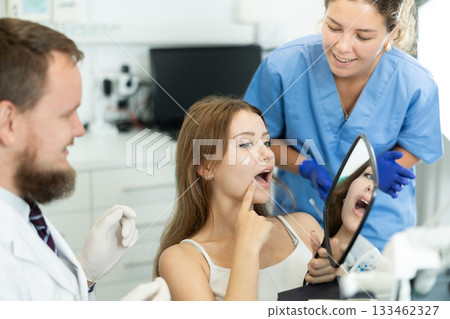 Woman at a dentist appointment with a man looking in the mirror 133462327