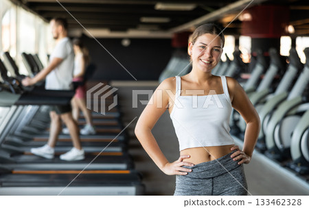 Young woman posing by treadmill in gym 133462328