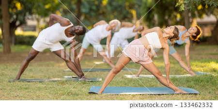 People of different ages and nationalities practice various yoga poses in summer garden People of different ages and nationalities practice various yoga poses in summer garden 133462332