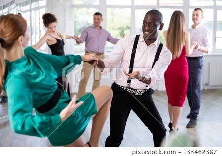 Woman dances incendiary boogie woogie with African man partner during choreography lesson 133462387