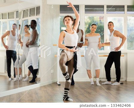 Female ballet instructor demonstrating movements to group of dancers Female ballet instructor demonstrating movements to group of dancers 133462406