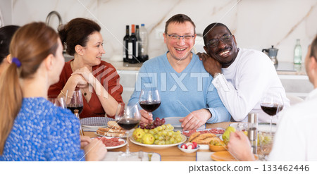 Companions congregated around a festive table, participating in animated discussions and enjoying the delights of red wine 133462446