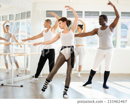 Group of men and women of different nationalities rehearsing ballet movements in studio 133462467