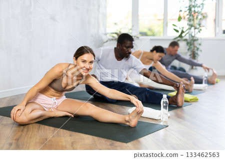Young woman doing yoga in group in studio 133462563