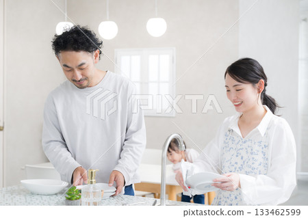 A couple washing dishes in the kitchen. An image of both spouses working. 133462599