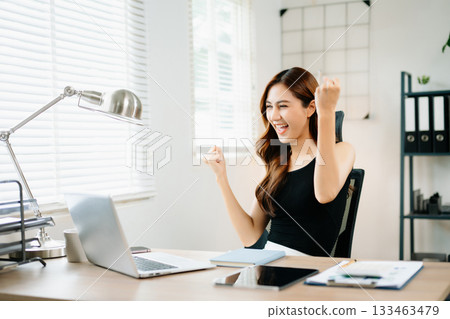 Cheerful businesswoman celebrating success at work, raising fists in joy at laptop, symbolizing achievement, motivation Cheerful businesswoman celebrating success at work, raising fists in joy at laptop, symbolizing achievement, motivation 133463479