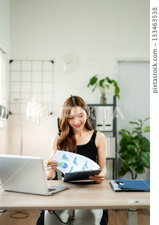 Confident Asian woman with a smile standing holding notepad and tablet at the modern office. Confident Asian woman with a smile standing holding notepad and tablet at the modern office. 133463538