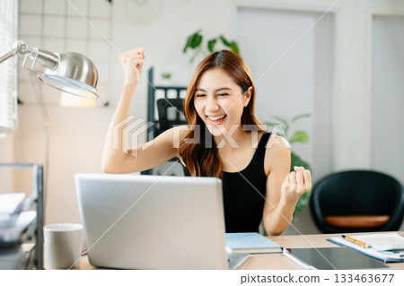 Cheerful businesswoman celebrating success at work, raising fists in joy at laptop, symbolizing achievement, motivation Cheerful businesswoman celebrating success at work, raising fists in joy at laptop, symbolizing achievement, motivation 133463677