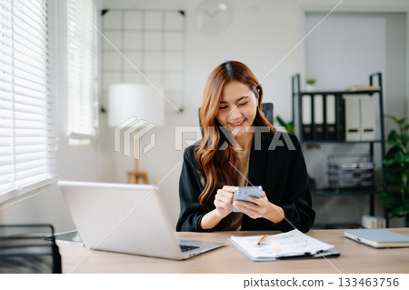 Asian businesswoman working in the office with working notepad, tablet and laptop documents Asian businesswoman working in the office with working notepad, tablet and laptop documents 133463756