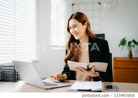 Confident Asian businesswoman presenting chart and data report in modern office. Perfect for marketing, finance, analysis, and professional business strategy concepts. 133463808