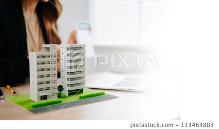 Real estate broker agent presenting and consult to customer to decision making sign insurance form agreement, home model, concerning mortgage loan offer in office Real estate broker agent presenting and consult to customer to decision making sign insurance form agreement, home model, concerning mortgage loan offer in office 133463883