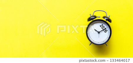 2025 and 2026 on black alarm clock on yellow background, 133464017