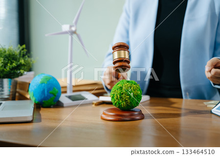 A gavel strikes a green planet symbolizing eco justice as two professionals review contracts for sustainable energy policy, climate law, A gavel strikes a green planet symbolizing eco justice as two professionals review contracts for sustainable energy policy, climate law, 133464510
