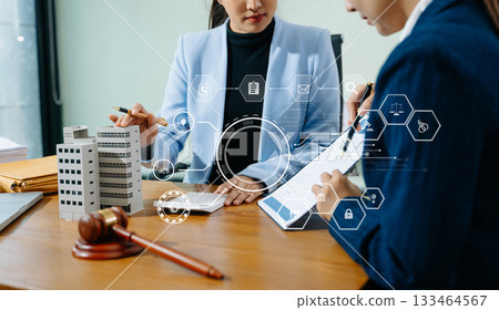 Female lawyer and client discuss legal contract with digital finance icons. Modern law, real estate, tech innovation, and business consulting in one powerful scene. 133464567