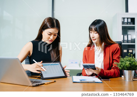 Businesswomen work and discuss their business plans. A Human employee explains and shows her colleague the results paper Businesswomen work and discuss their business plans. A Human employee explains and shows her colleague the results paper 133464769