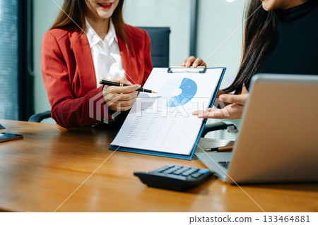 Business documents on office table with smart phone and calculator digital tablet and graph business with social network diagram and two colleagues discussing data 133464881