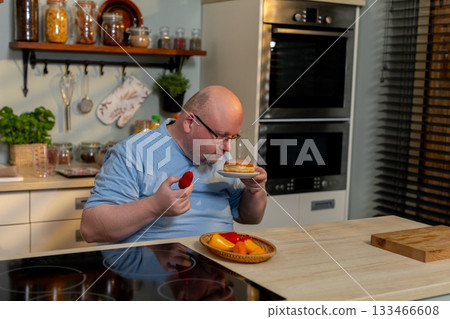 Mature male chef sampling flavorful soup in cozy kitchen environment, Elderly man with apron tasting freshly prepared soup amid kitchen with herbs and modern appliances 133466608
