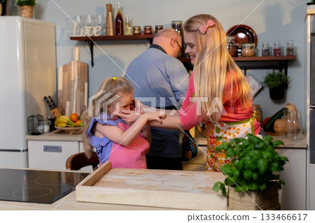 Family embrace cooking, Warm evening scene of family sharing loving hug in kitchen space, Playful and heartfelt scene of parents and child enjoying cooking together at home Family embrace cooking, Warm evening scene of family sharing loving hug in kitchen space, Playful and heartfelt scene of parents and child enjoying cooking together at home 133466617