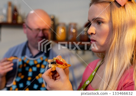 Child enjoys cheesy pizza, Young girl eats in kitchen, Nostalgic scene of girl eating pizza with family, Casual moment of young girl enjoying cheesy pizza amidst homecooked setting Child enjoys cheesy pizza, Young girl eats in kitchen, Nostalgic scene of girl eating pizza with family, Casual moment of young girl enjoying cheesy pizza amidst homecooked setting 133466632