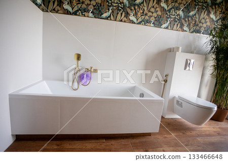 Sleek bathtub and modern toilet arrangement with gold tap and tile floor, window light and calm designercurated vibe showcasing sustainable materials for eco-conscious interiors 133466648
