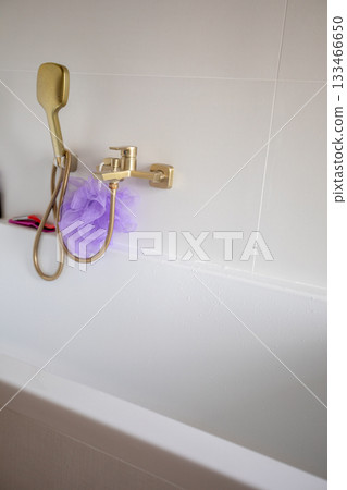 Refined white bathtub corner with metallic accents and soothing ambiance, Homeowner prepares for relaxing evening bath with stylish fixtures and cozy atmosphere Refined white bathtub corner with metallic accents and soothing ambiance, Homeowner prepares for relaxing evening bath with stylish fixtures and cozy atmosphere 133466650