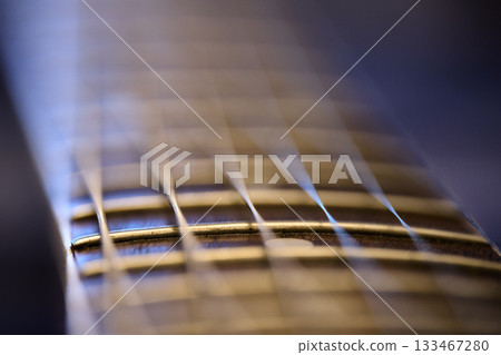 Guitar neck shows detailed strings and frets in soft light. 133467280